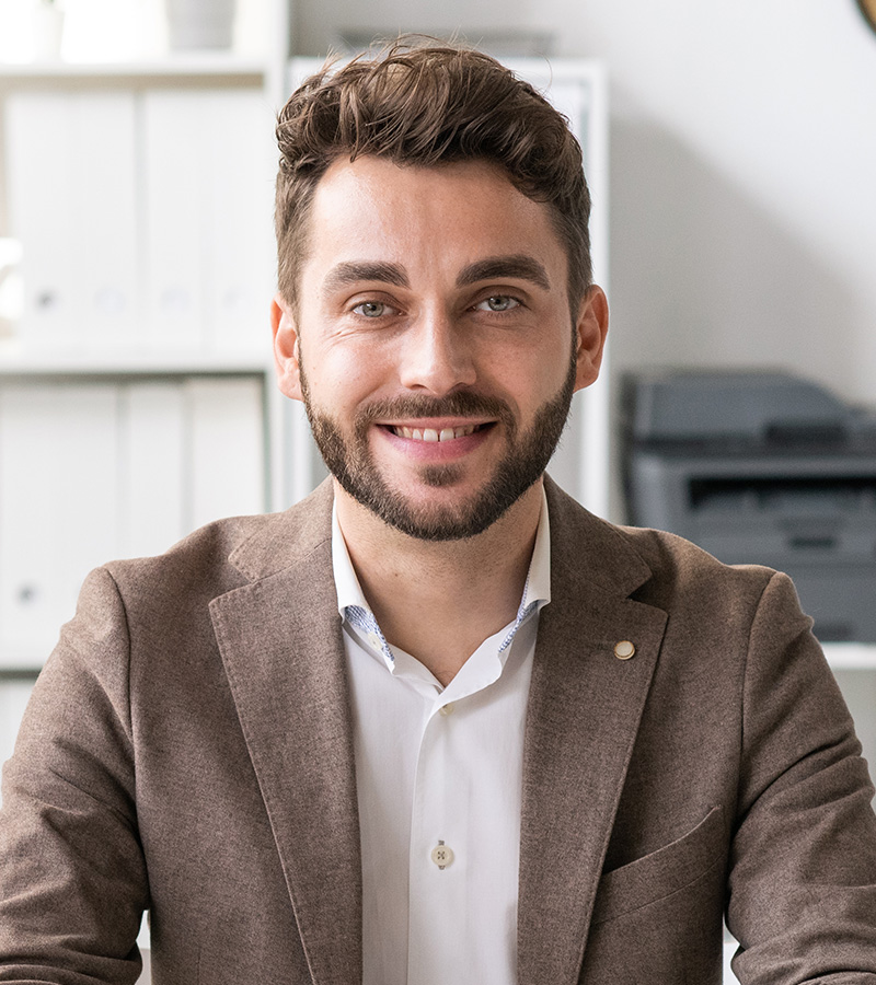 happy young lawyer in formalwear sitting by desk i T7MFNTV 1